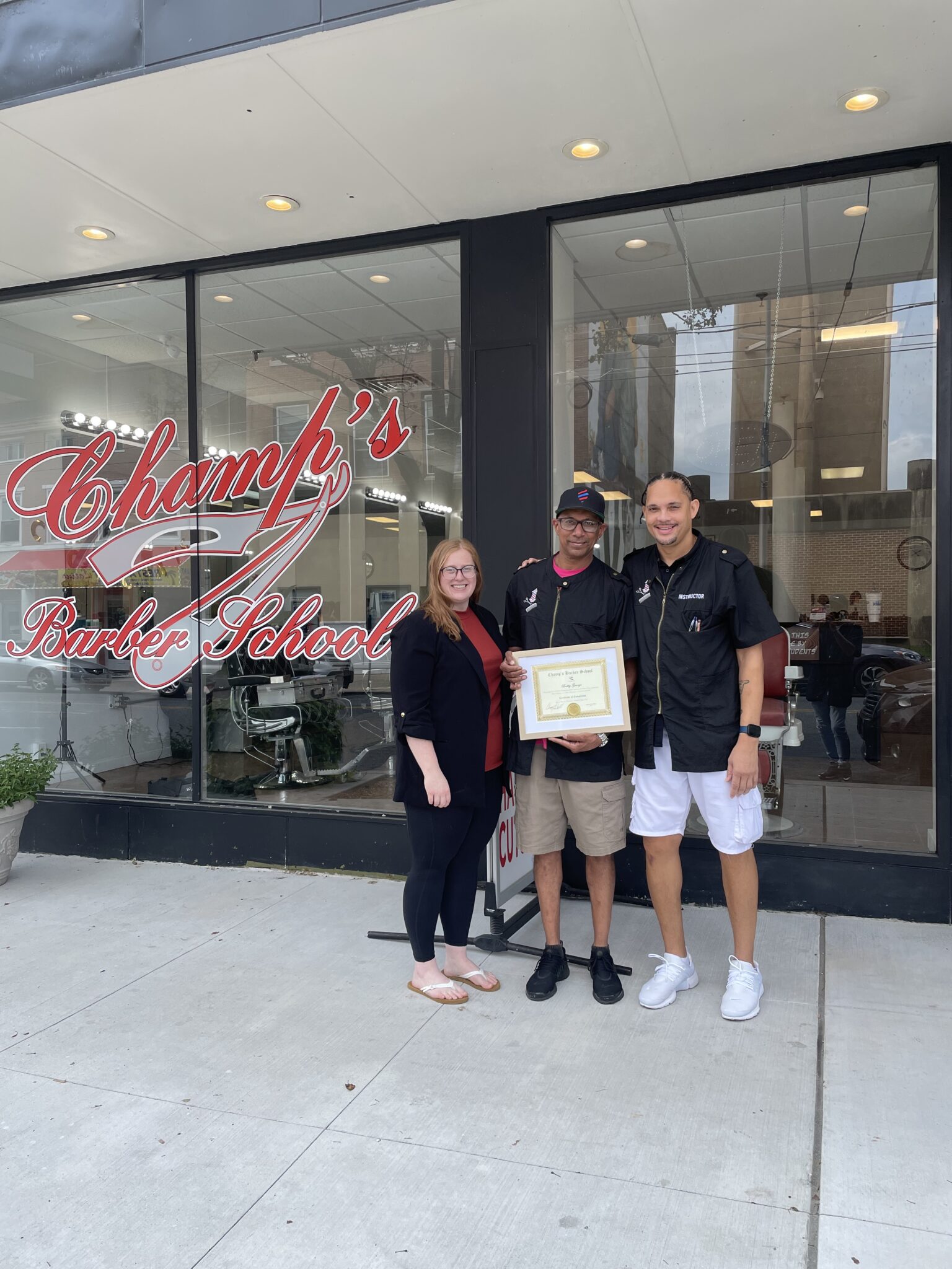 Three people stand outside Champ's Bar & Grill holding a certificate.